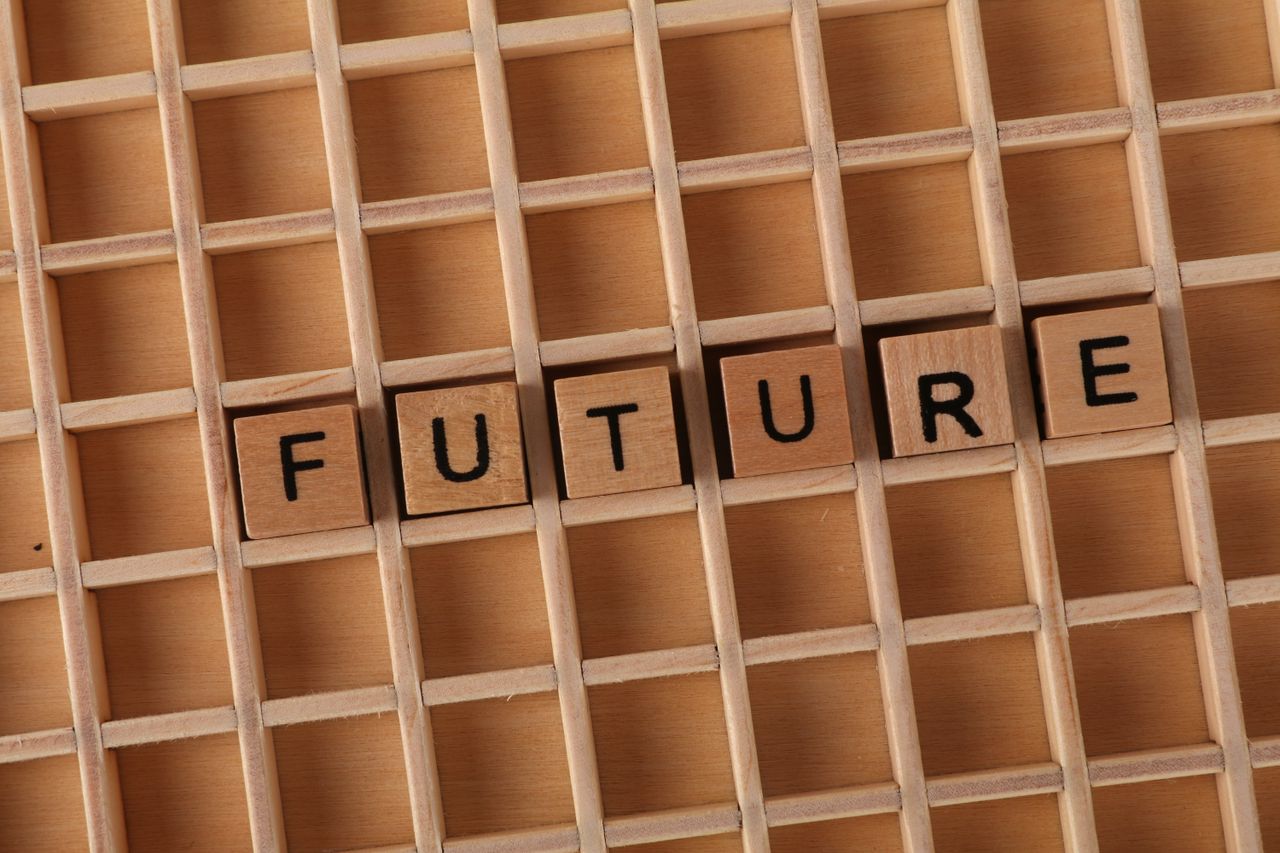 About Wooden letter blocks spell 'FUTURE' on a wooden grid background.