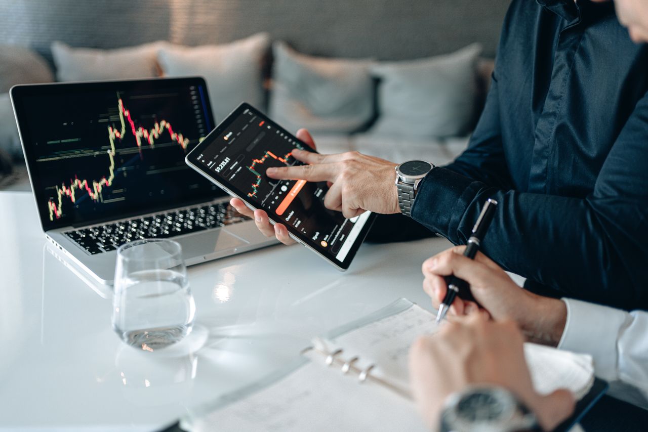 Home Professionals analyzing financial data on a tablet and laptop in an office setting.