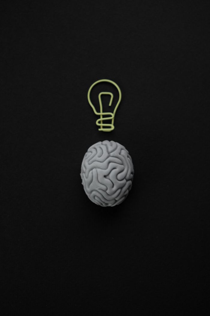 Services Gray brain with light bulb symbol on black background representing intelligence and creativity.